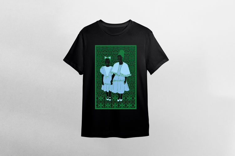 A black short-sleeve crewneck t-shirt featuring a rectangular graphic print on the front. The graphic depicts two young black children in light blue sunday dresses standing against a dark green african patterned background.